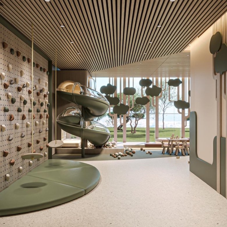 Salle de jeux intérieure pour enfants avec mur d’escalade et toboggan au projet Cybel by Wadan à Dubai Land Residence Complex